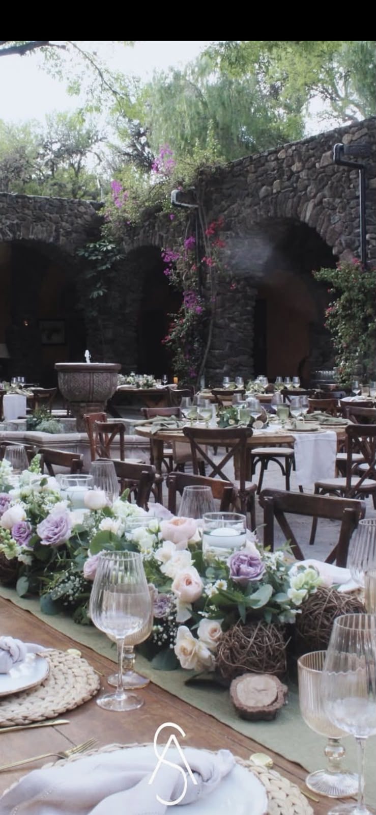 Mesa de banquete en jardín frente a muro de piedra en Hacienda Dolores, Querétaro