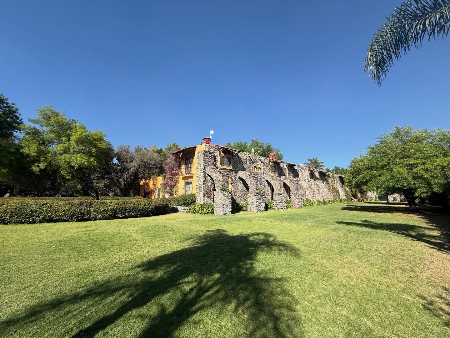 Panorámica de los jardines de Hacienda Dolores con la fachada de arcos de piedra del siglo XVII, salón de eventos en Querétaro