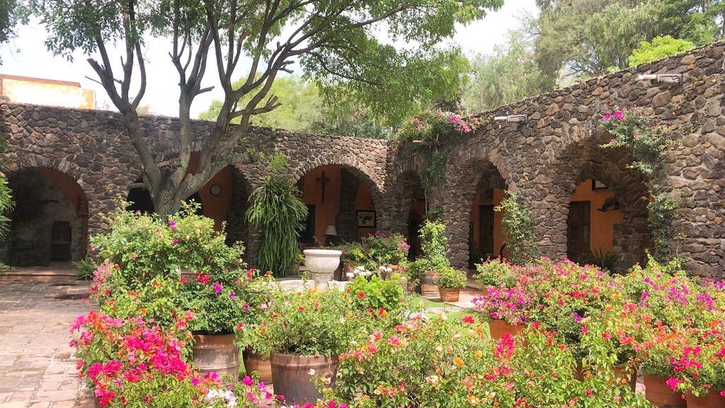Patio con arcos de piedra y jardín en Hacienda Dolores, Querétaro
