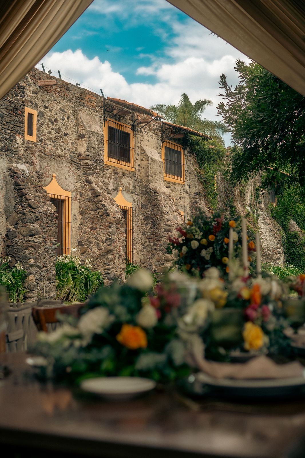 Pista de baile con arreglos florales frente al muro de piedra en Hacienda Dolores, Querétaro